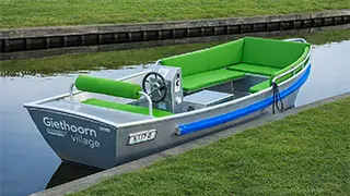 A boat with soft cushions and a steering wheel for 5 to 8 people that you can rent at Giethoorn boat tickets