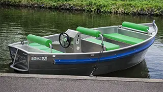 A boat with soft cushions and a steering wheel for 3 to 5 people that you can rent at Giethoorn boat tickets