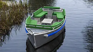 A boat with soft cushions and a steering wheel for 6 to 10 people that you can rent at Giethoorn boat tickets